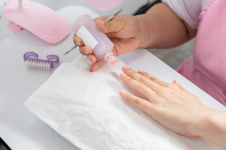 close-up of the hands of a young woman applying liquid nail polish remover to her nailsの写真素材