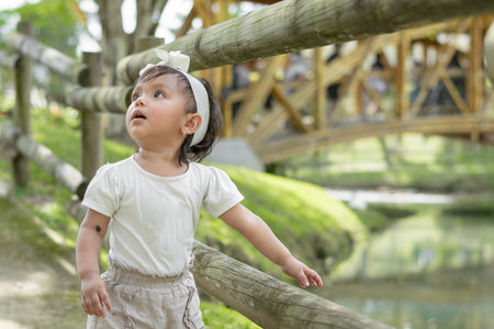 little latina girl, astonished, pointing curiously at what she is looking at in the parkの写真素材