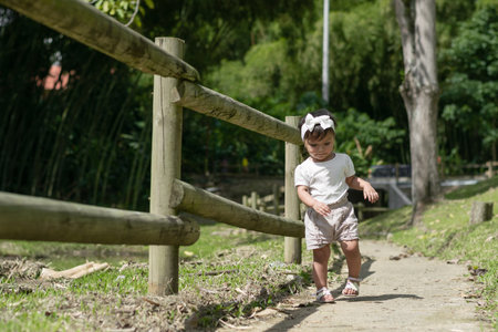 little brunette latina girl learning to walk along a path in a parkの写真素材