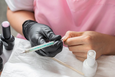 close-up of the hands of a woman decorating her nails with a manicure brushの写真素材