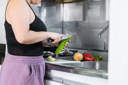 close-up of a young latin woman removing the peel of a green banana to make pataconesの写真素材