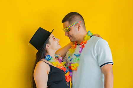 young latin couple, facing each other smiling while dressed in party clothes, yellow background. carnival conceptの写真素材