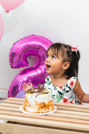 little latin brunette girl looking up very happy on her birthday, yellow cake