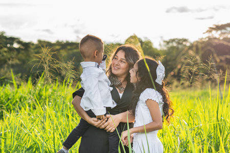 latin family, young mother with her daughter looking attentively at what her young son is saying,...