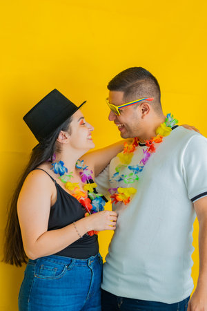 young latin couple, laughing loudly while facing each other, with flower necklaces. yellow backgroundの写真素材
