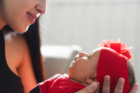 close-up of newborn baby girl looking at her mother while being carried in her handsの写真素材