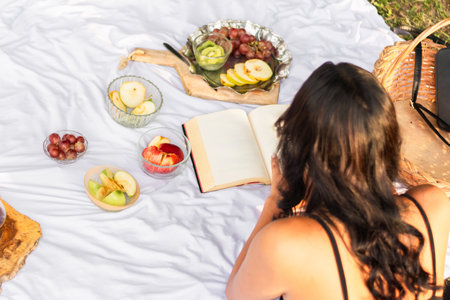 zenithal shot of girl lying on the ground reading a book, picnic dayの写真素材