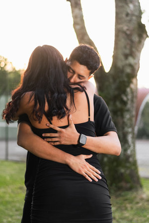 young latin couple hugging each other very much in love with closed eyes at sunset