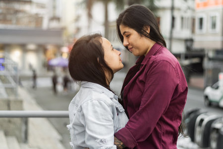 two latin lesbian women looking at each other in the eye while smiling, couple on the streets of a south american cityの写真素材