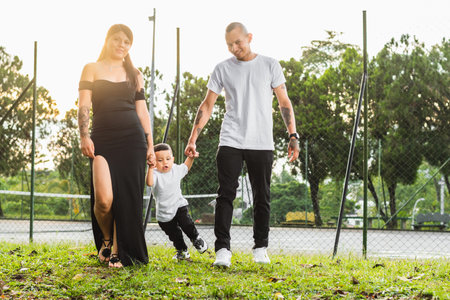young latin couple taking a walk in the park with their young son