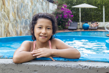 Girl in outdoor pool enjoying a summer day in a relaxed family environmentの写真素材