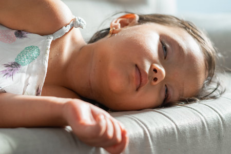 Young child asleep on couch with arm forward, soft light and shallow focus, quiet afternoon rest.の写真素材