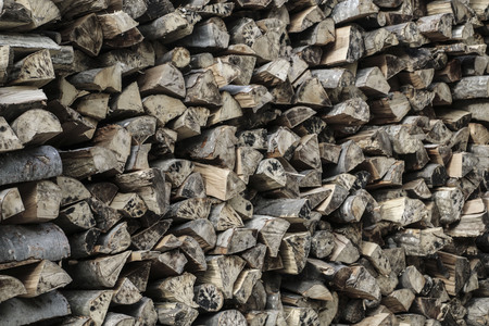 Natural wood background, logs of chopped firewood are stacked in a row