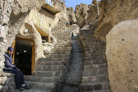 KANDOVAN, IRAN - SEPTEMBER 27, 2018: Elderly Iranian man  is sitting near the entrance to the store in rock village Kandovan.  Iranのeditorial素材