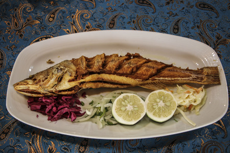 Fish dish cooking with various ingredients with lemon, garlic, herbs and spices. Healthy food or...