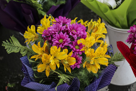 Bouquet yellow lilies and purple chrysanthemums, wrapped in a decorative package with a print