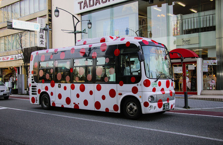 MATSUMOTO, JAPAN- MARCH 26, 2019: City bus with bright red circles on a white background on a street in the city Matsumotoのeditorial素材