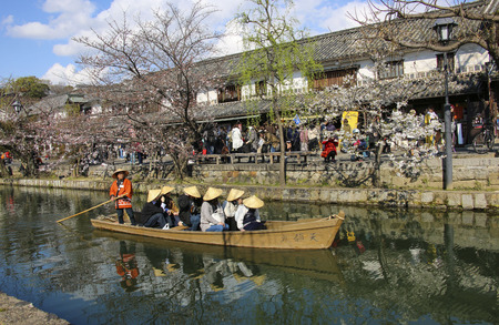 KURASHIKI, JAPAN - MARCH 31, 2019: Tourists are enjoying the old-fashioned boat along the Kurashiki canal in Bikan district of Kurashiki city, Japan.のeditorial素材