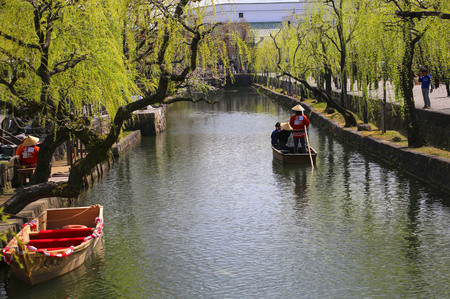 KURASHIKI, JAPAN - MARCH 31, 2019: Tourists are enjoying the old-fashioned boat along the Kurashiki canalのeditorial素材