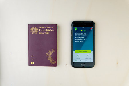 Lisbon, Portugal - January 2nd, 2021: Overhead shot of portuguese passport and smartphone showing TAP Air Portugal APP on screen with Covid-19 related message. Illustrative editorial.のeditorial素材