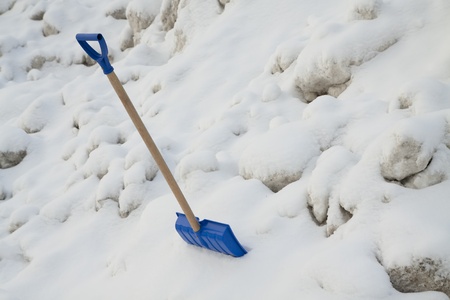 Blue plastic shovel on a snow backgroundの写真素材