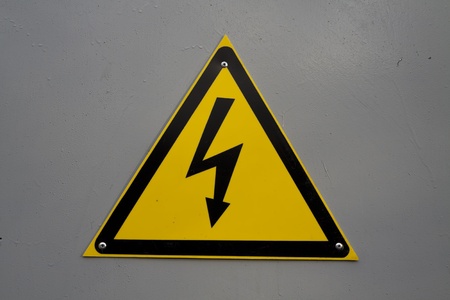 Yellow electricity warning sign on gray backgroundの写真素材
