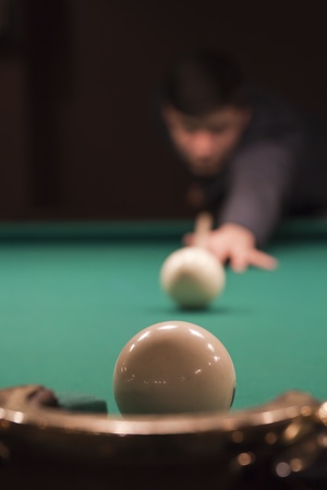 Hand holding billiard cue aimed at a white ballの写真素材