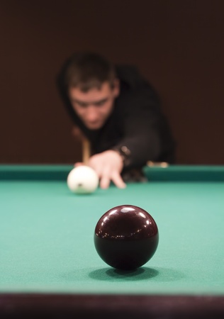 Hand holding billiard cue aimed at a black ballの写真素材
