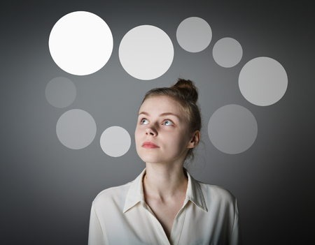 Girl in white having an idea with gray bubbles over her head. Young slim woman.の写真素材