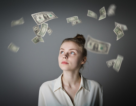 Girl in white and falling dollar banknotes. Currency and lottery concept. Young slim woman.の写真素材