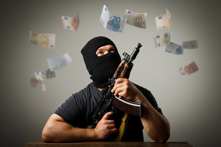Man in mask with gun and falling euro banknotes.