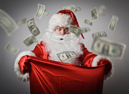 Shocked Santa Claus is looking in to the sack with dollars. Consumerism concept.の写真素材
