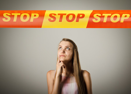 Woman and STOP line over her head. Restricted area concept. Young woman is doing something.の写真素材