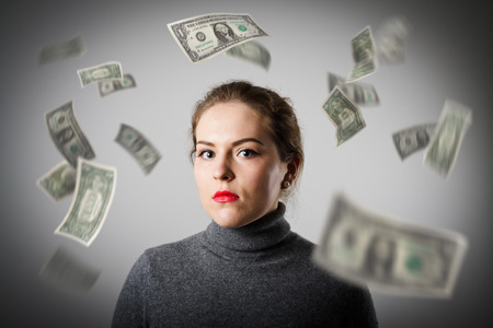 Girl in grey and falling dollar banknotes. Currency and lottery concept.の写真素材