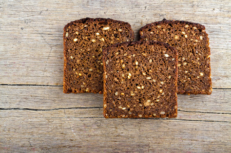 Slices of whole grain brown bread on wooden table.
