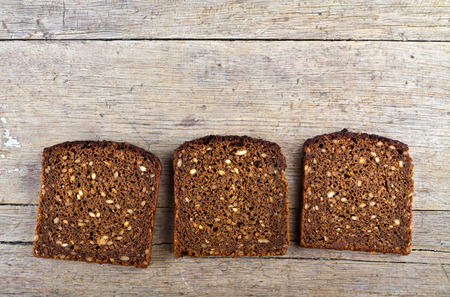 Slices of whole grain brown bread on wooden table.