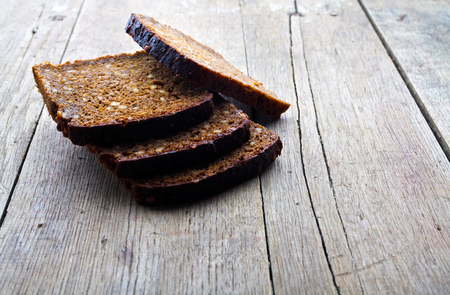 Slices of whole grain brown bread on wooden table.の写真素材