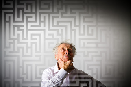 Old man in white is looking for the solution. Maze concept.の写真素材