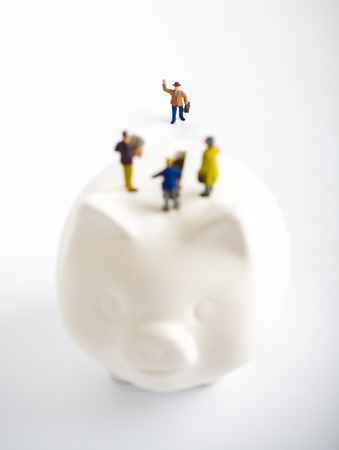 Businessman figurines on a piggybank. Money, business and expectation concept.の写真素材