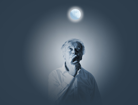 Old man in white and moon. Full moon and sleeplessness concept.の写真素材
