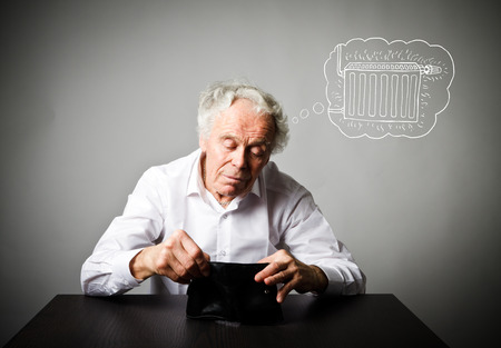 Old man in white and heating season. Heating season, taxes and saving concept. Radiator.
