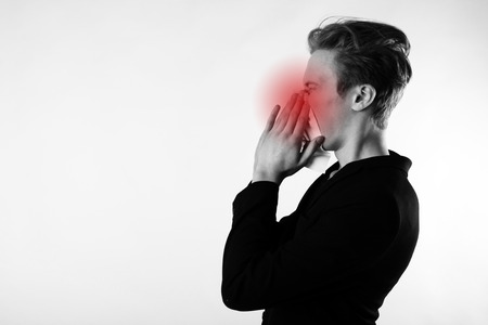 Sneeze. Young man in black is sneezing. Allergy concept.の写真素材