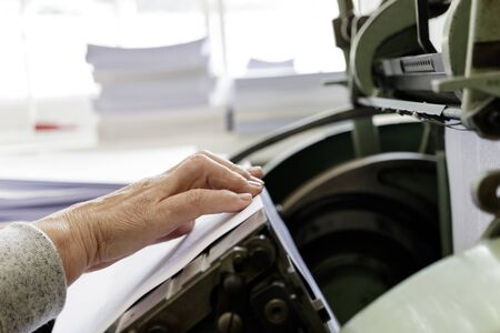 Machine for stitching book pages with threads in typography. Machine for sewing books and notebooks with threads. Women at work.の写真素材