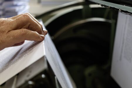 Machine for stitching book pages with threads in typography. Machine for sewing books and notebooks with threads. Women at work.の写真素材