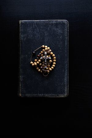 Rosary beads and prayer book. Rosary and book of Catholic Church liturgy on dark background.の写真素材