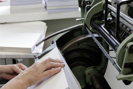 Machine for stitching book pages with threads in typography. Machine for sewing books and notebooks with threads. Women at work.の写真素材
