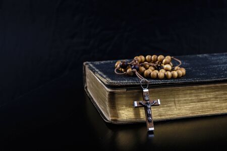 Rosary beads and prayer book. Rosary and book of Catholic Church liturgy on dark background.の写真素材