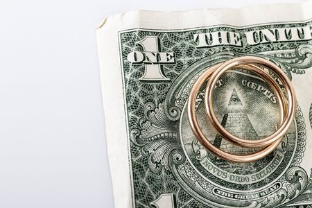 Two wedding rings and currency. Wedding rings and one dollar. Wedding or divorce concept. Wedding Planning concept. Expenses.の写真素材