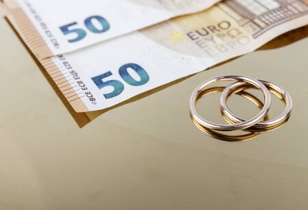 Two wedding rings and currency. Wedding rings and fifty euro. Wedding or divorce concept. Wedding Planning concept. Expenses.の写真素材