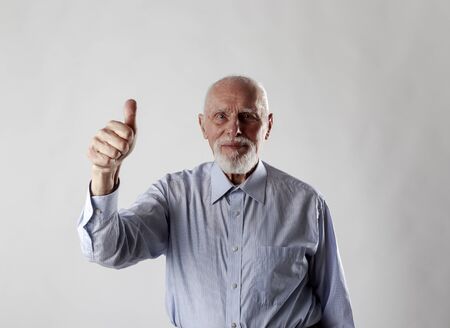 Old man is showing thumb up. Success, happiness and good health.